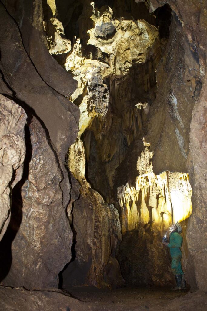 Une grotte de l'intérieur, un spéléologue éclaire le haut.