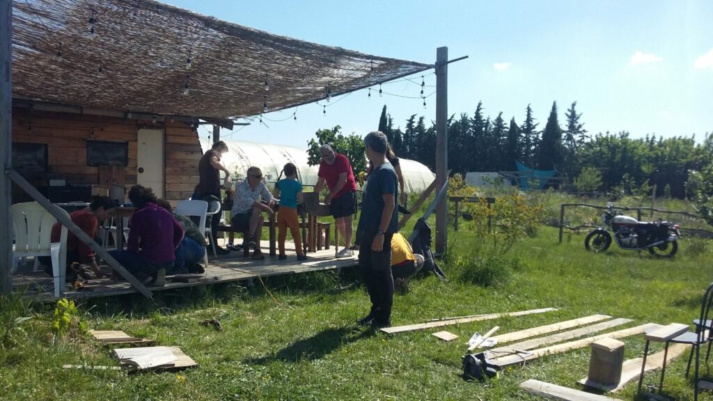 Des personnes sous une tonnelle, dans un jardin, construisent des nichoirs