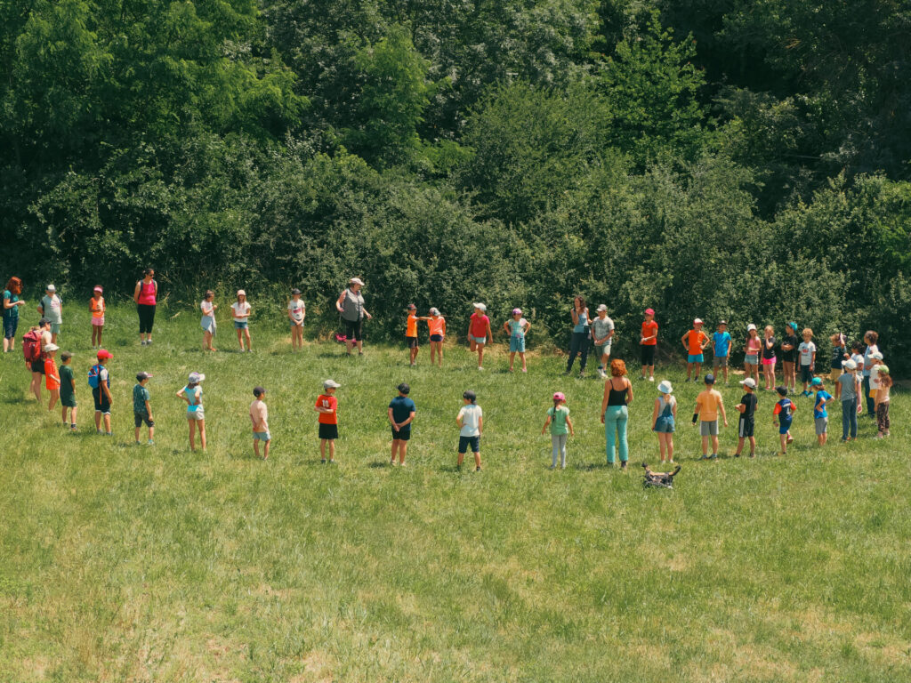 Une trentaine d'enfants sont en cercle dans une prairie